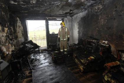 Firefighter Ross Henderson in the living room that had no sprinkler system or smoke detector fitted